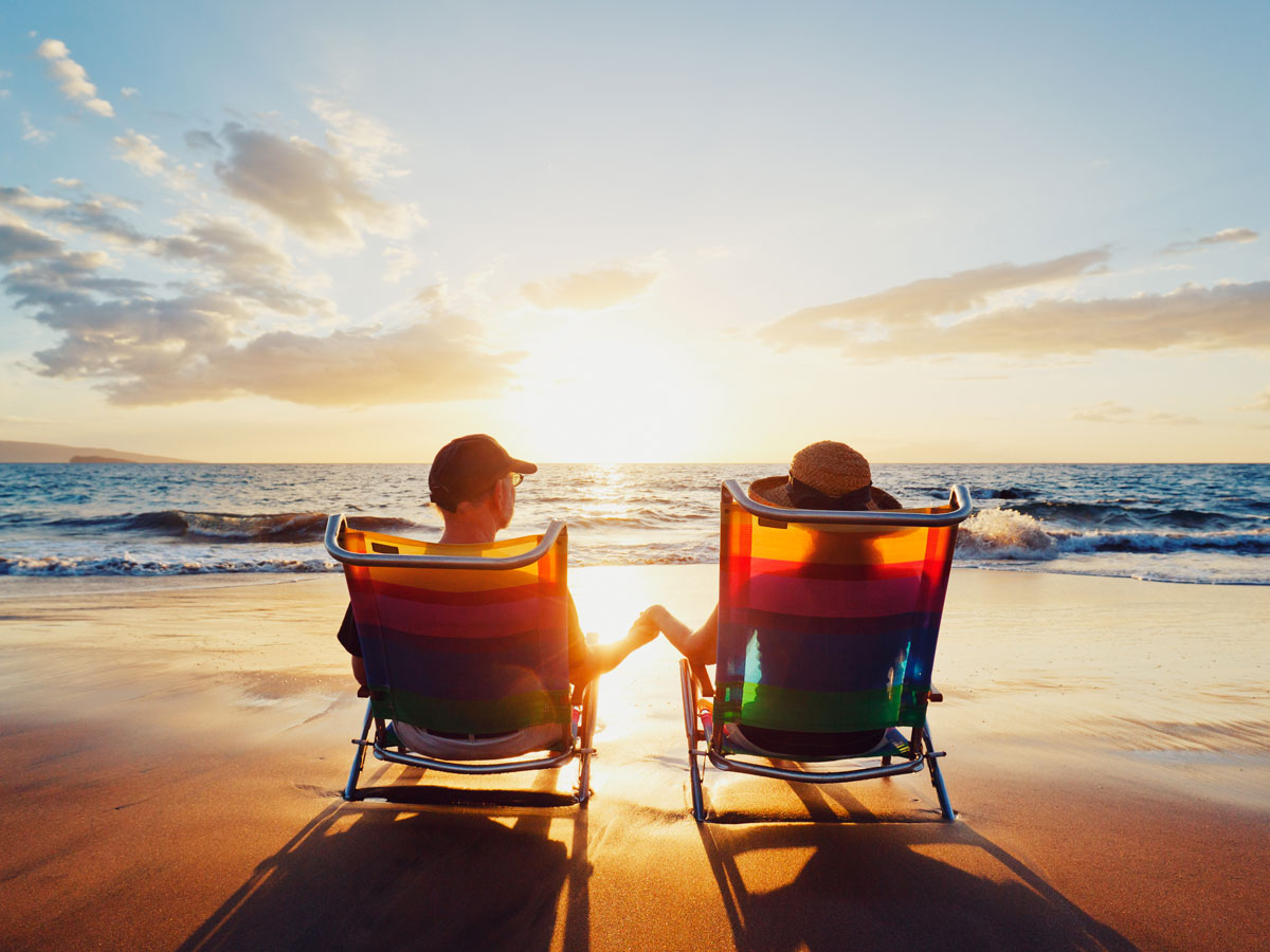 Couple on beach chairs holding hands enjoying sunset at the beach