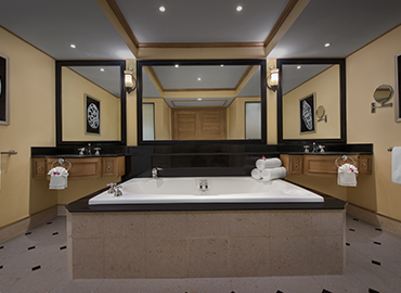 Spacious villa bathroom with large tub, mirrors, and white bath towels