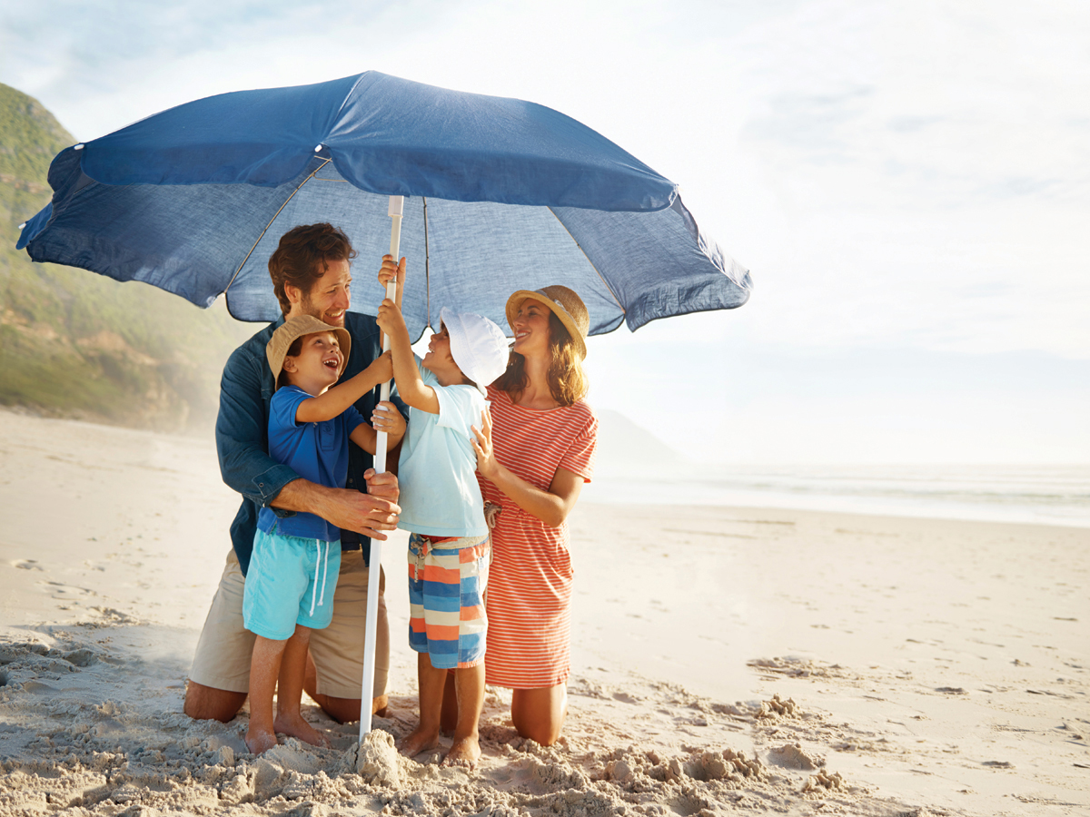 Family on beach relaxing under large shade umbrella