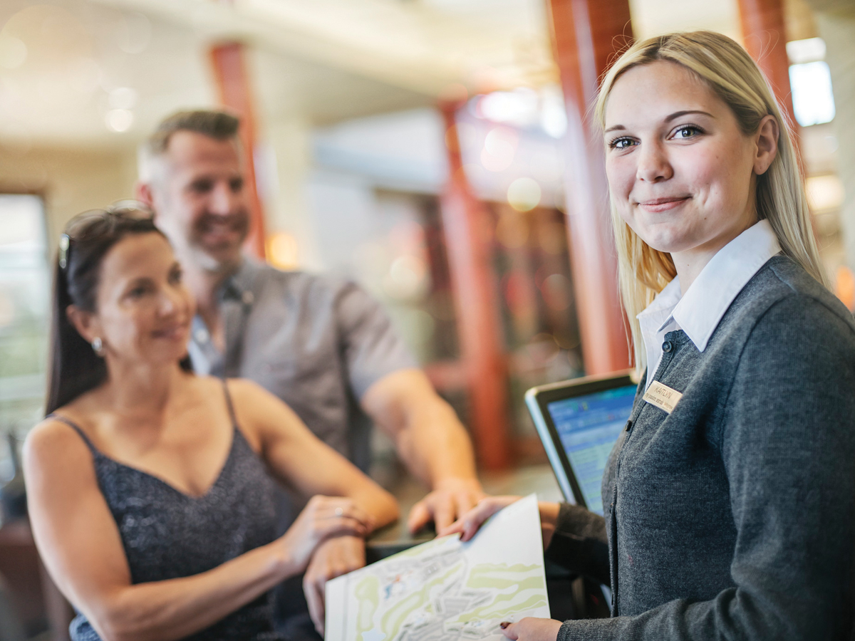 Friendly resort staff member helping happy guests