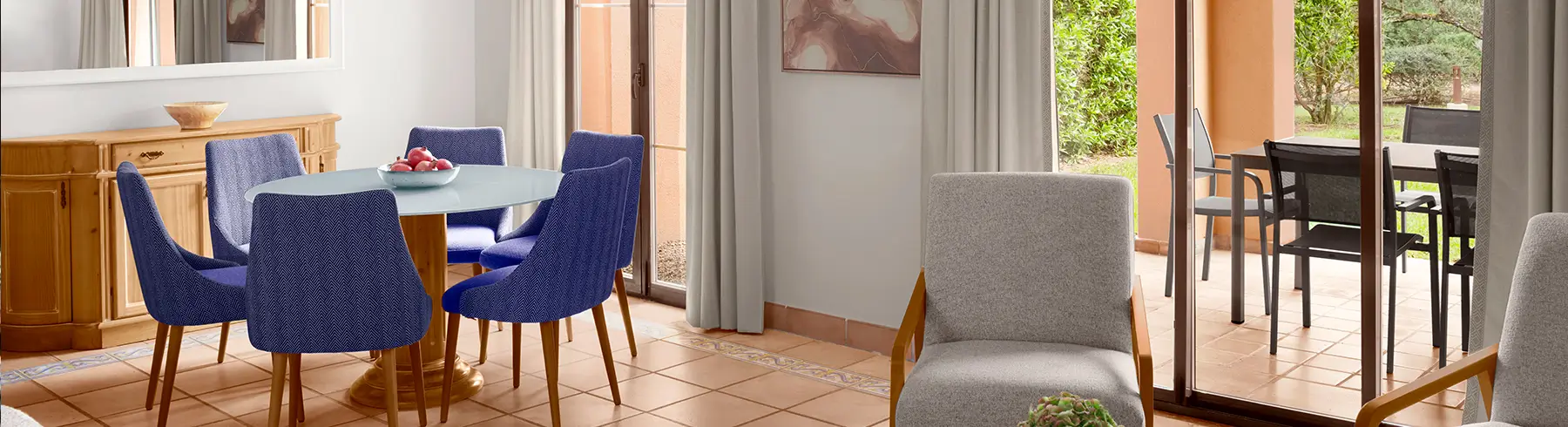 Elegant living and dining area at Marriott's Club Son Antem featuring stylish blue chairs and a view of the outdoors.